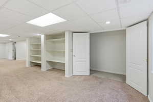 Spacious room featuring neutral carpeting, built-in shelving, two interior doors, recessed lighting, and a drop ceiling with integrated lighting panels