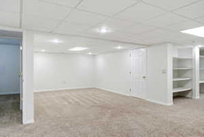 Spacious room featuring carpeting, white walls, recessed lighting, and built-in shelving