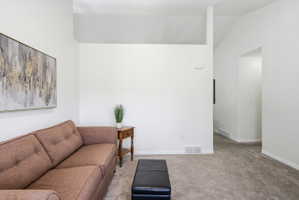 Spacious living area featuring neutral carpeting and crisp white walls