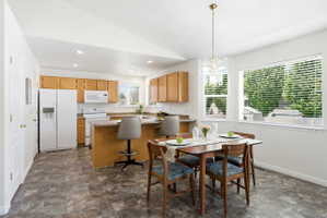 Kitchen and dining area featuring vaulted ceilings, recessed lighting, and wood-finish flooring