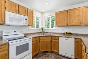 Kitchen featuring wood-finish cabinetry, patterned countertops, and a double basin stainless steel sink