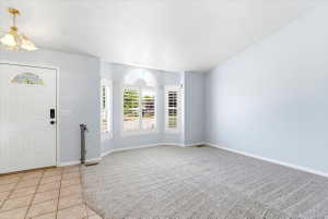Entryway featuring an arched decorative glass front door, ceramic tile flooring, and a chandelier with a brass finish