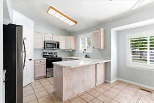 Kitchen featuring light wood-finish cabinetry, white countertops, and stainless steel appliances