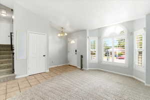 Living area with a large arched window featuring louvered shutters, carpet flooring, and a ceiling light fixture