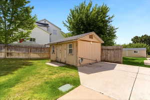 Expansive concrete pad leading to a detached utility shed with dual doors and multiple windows