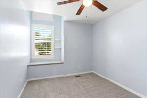 Window nook with custom plantation shutters, integrated window seat, ceiling fan with light fixture, and plush carpeting