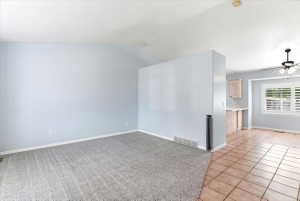 Spacious room featuring vaulted ceilings, light gray carpeting, and a half-wall partition