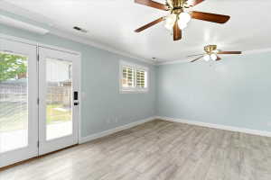 Room featuring light wood-finish flooring, light blue wall paint, and white crown molding