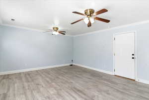 Spacious room featuring wood-finish flooring, light blue walls, and crown molding