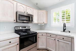 Kitchen featuring light-finish cabinetry with dark hardware, white countertops, and a double basin sink with a matte black faucet