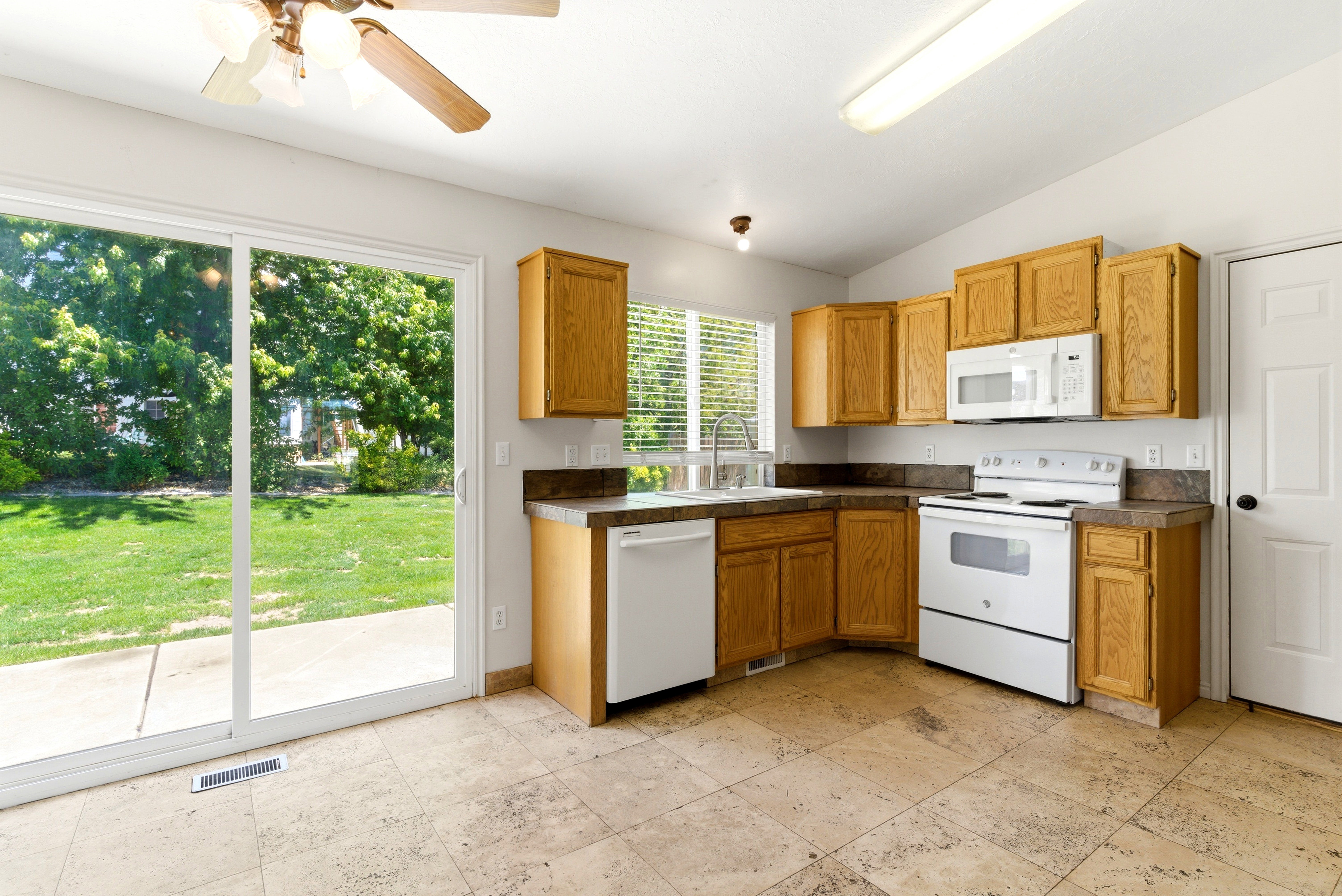 Kitchen featuring wood-finish cabinetry, white appliances, and a double-basin sink