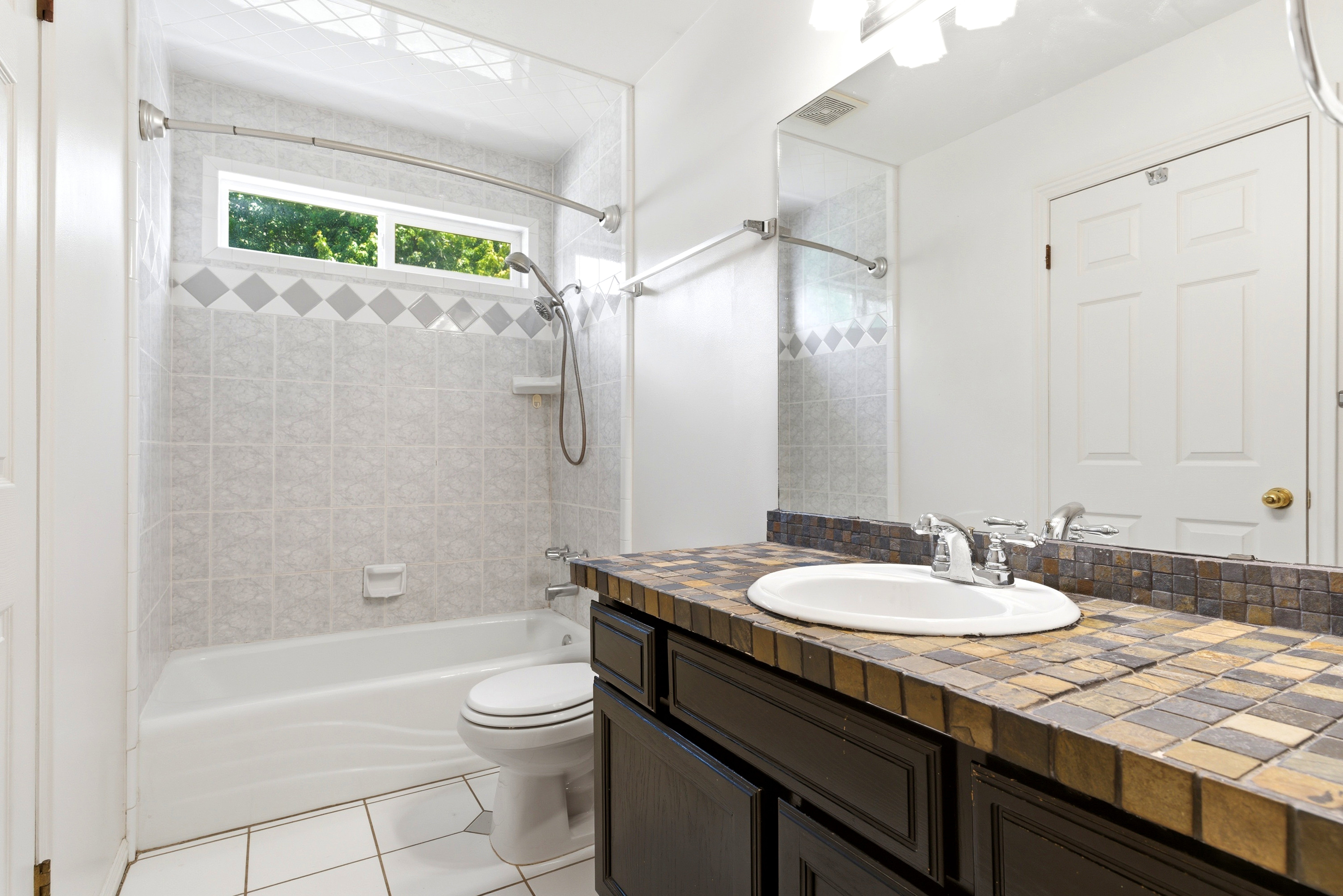 Bathroom featuring a built-in vanity with a tiled countertop, undermount sink, and chrome faucet