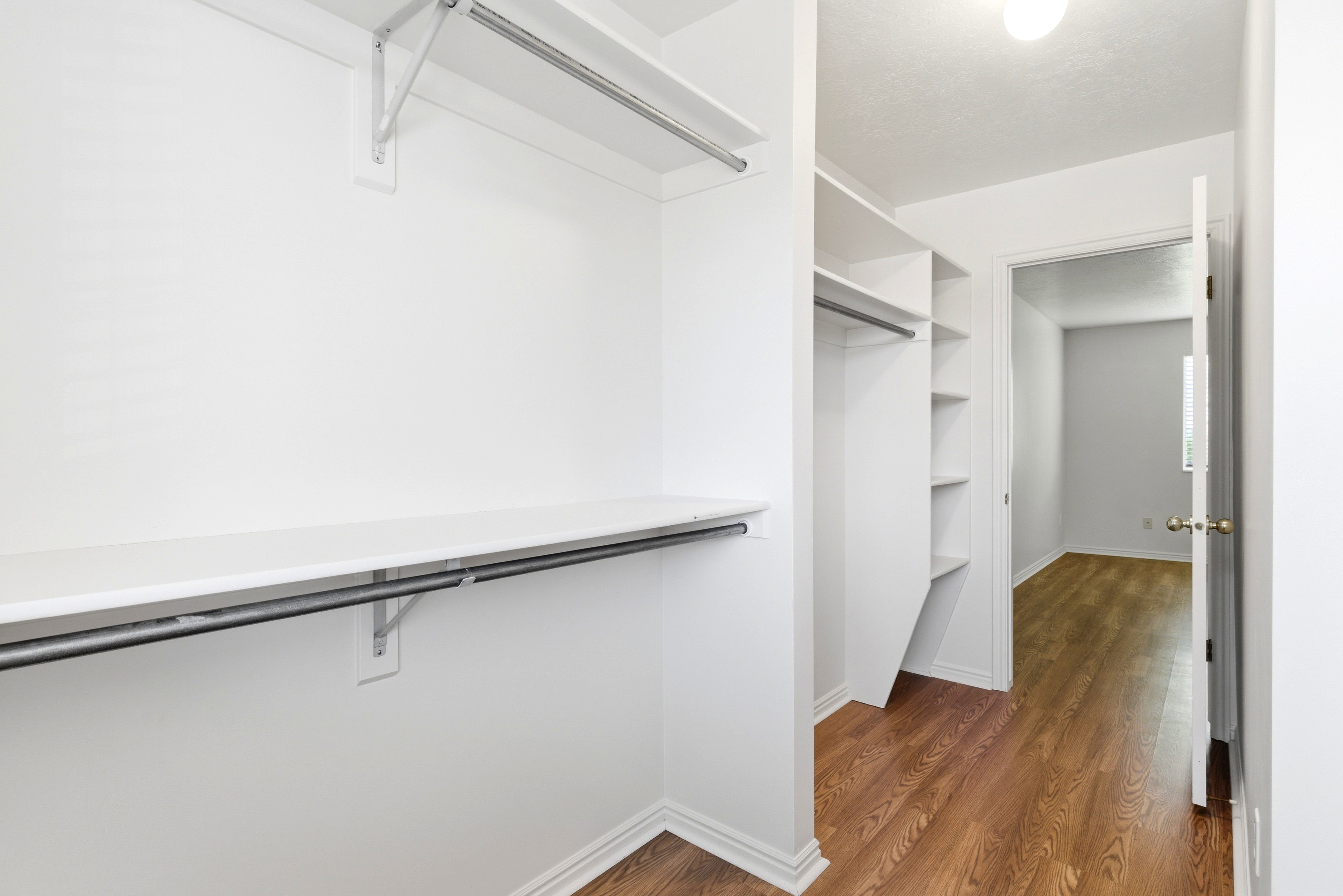 Walk-in closet featuring white shelving and hanging rods