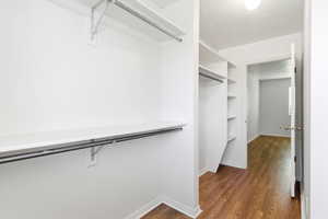 Walk-in closet featuring white shelving and hanging rods