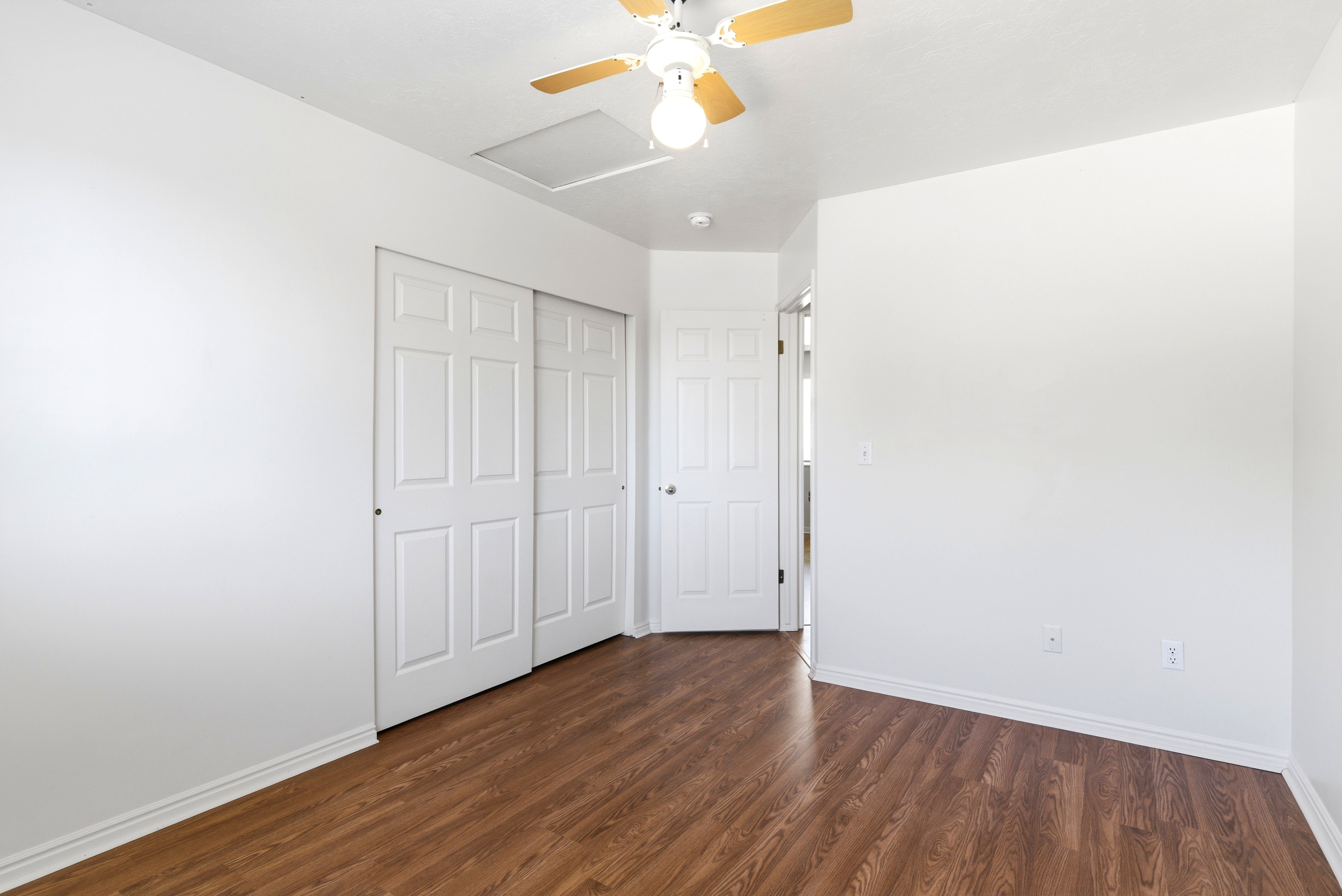 Room featuring wood-finish flooring, white baseboards, and white walls