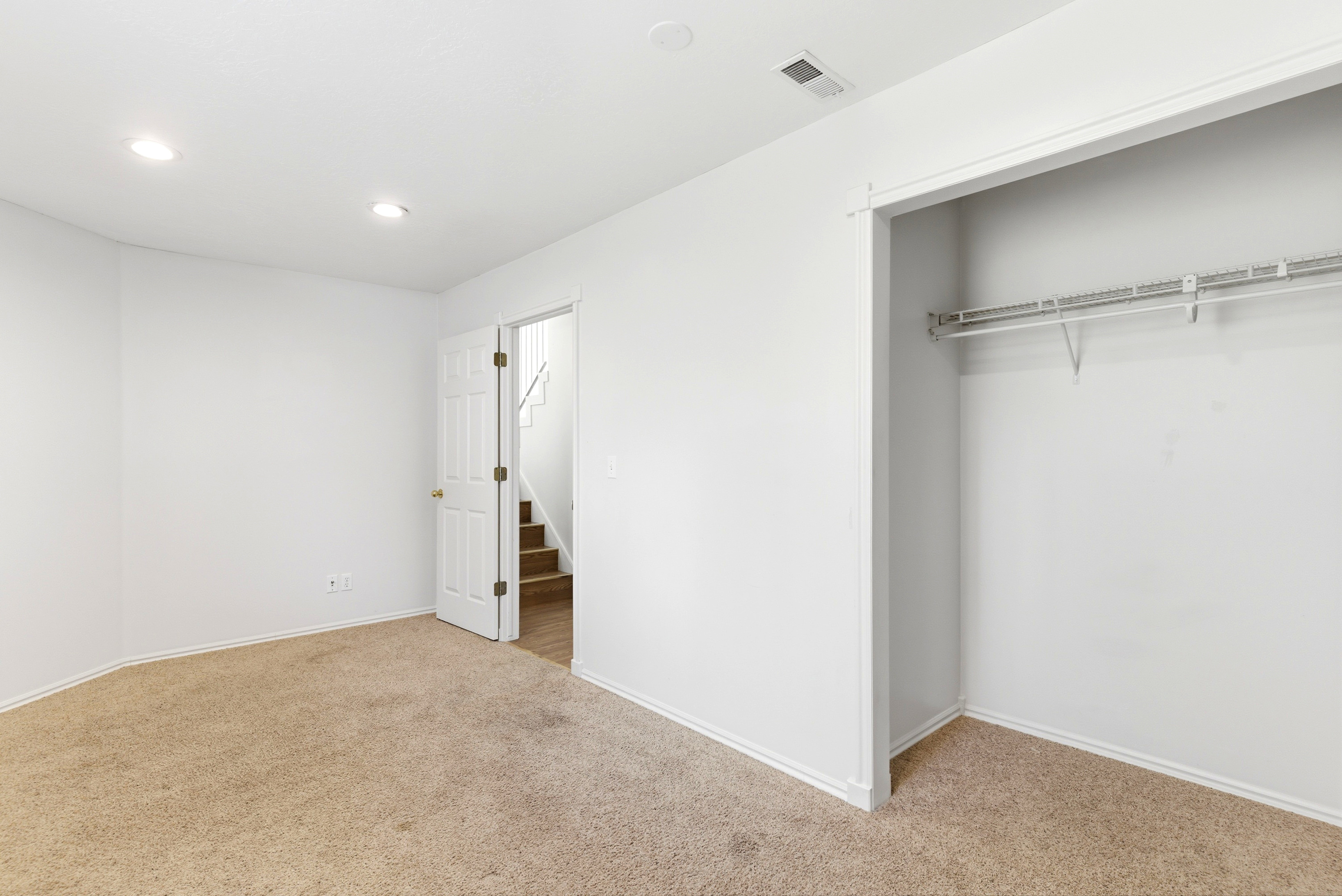 Neutral wall finishes with recessed lighting and carpeted flooring