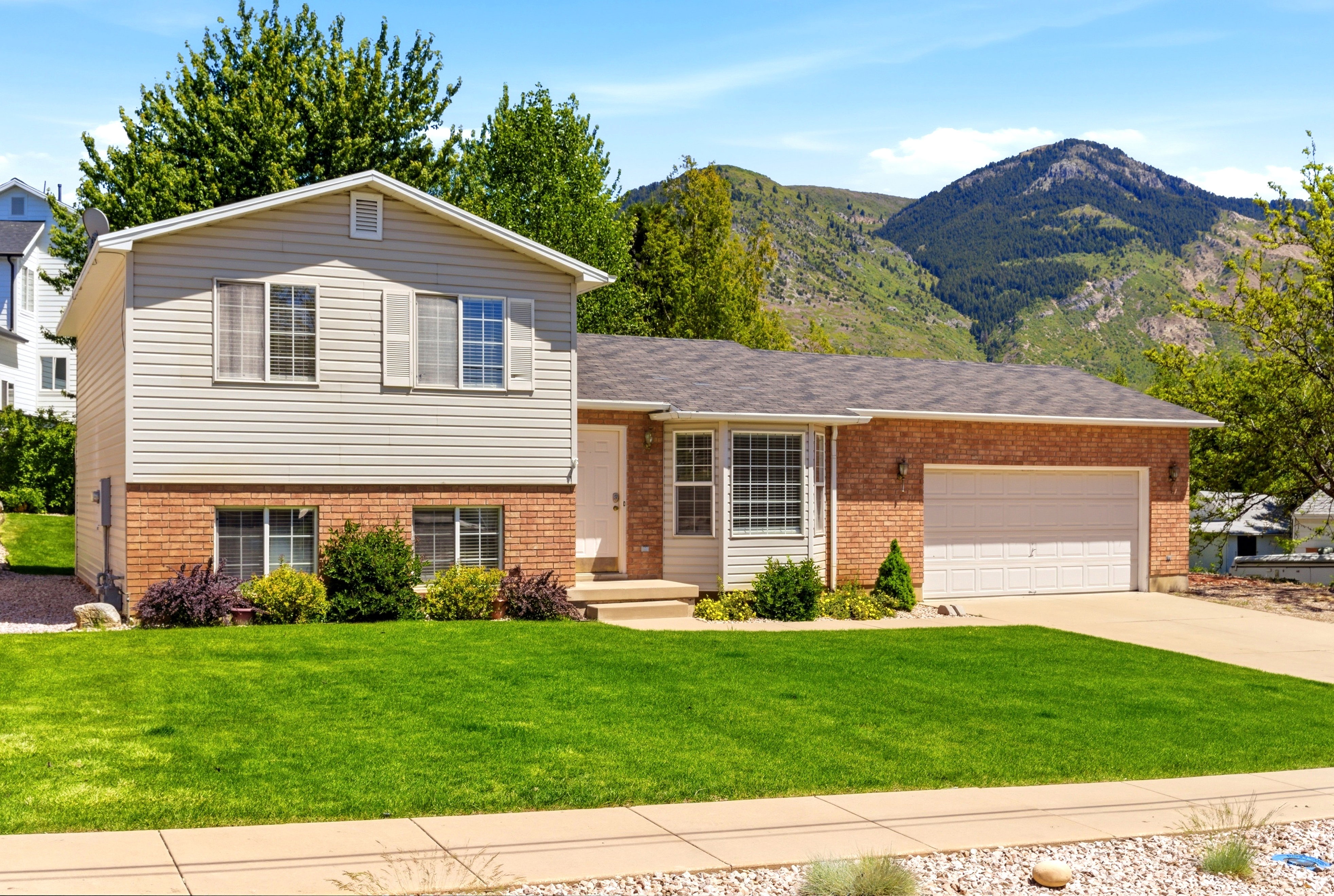Two-story residence featuring brick and siding facade, an attached garage, and a lush green lawn