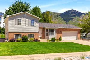 Two-story residence featuring brick and siding facade, an attached garage, and a lush green lawn
