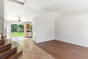 Open-concept living space with vaulted ceilings, wood-finish flooring, and a sliding glass door providing natural light