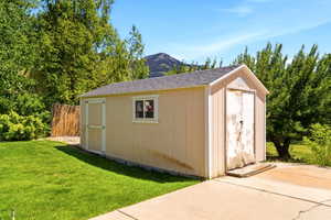 Detached utility shed with a shingle roof, single window, and two entry doors, situated on a concrete slab