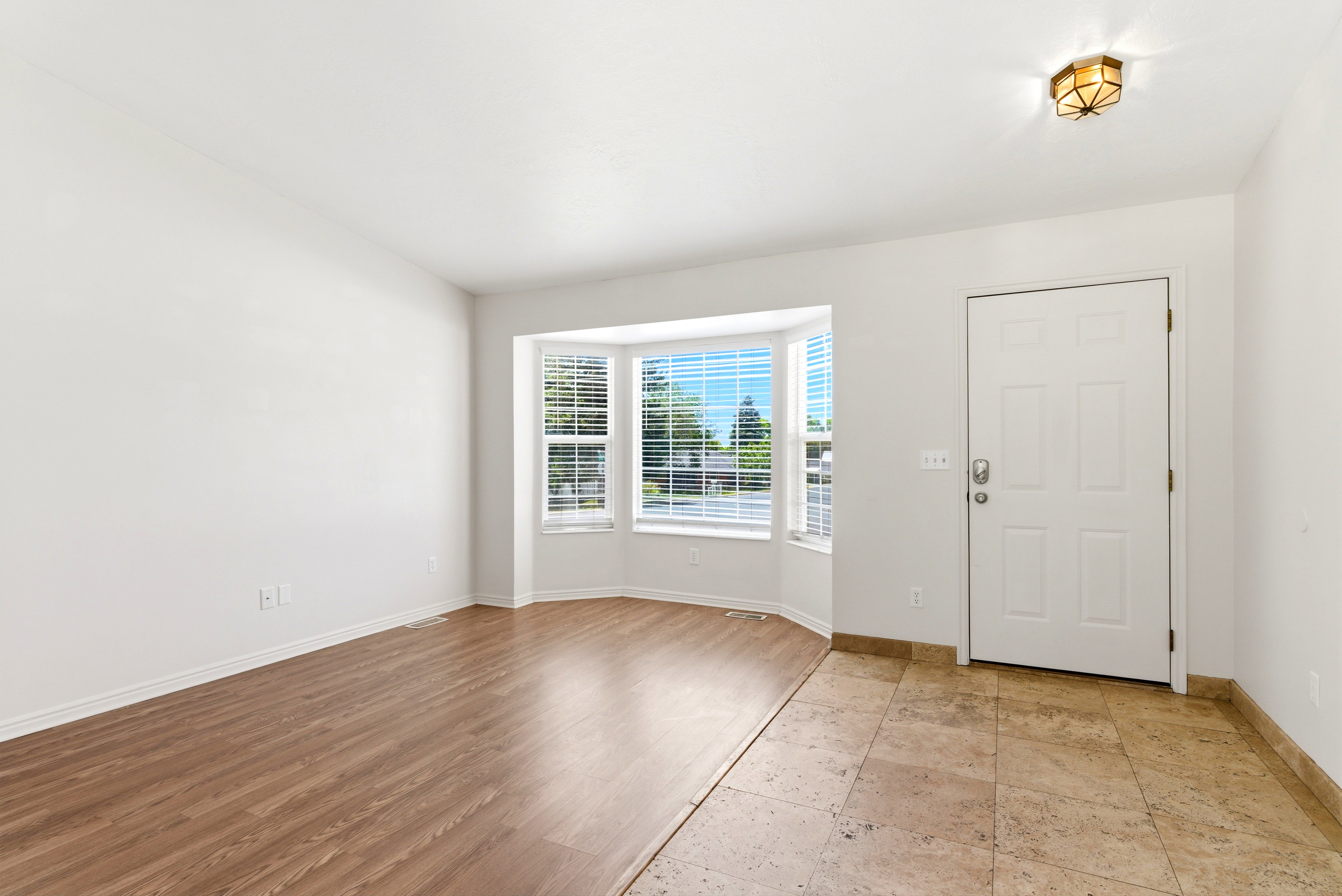 Entryway featuring a white paneled door, flush-mount lighting, and a bay window