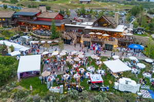 Expansive outdoor event space featuring manicured lawns and stone-clad buildings with multiple balconies