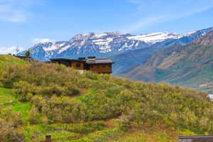 Modern mountain home featuring a dark flat roof, warm wood siding, and multiple visible chimneys