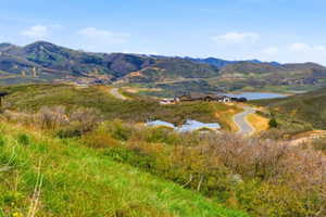 Expansive mountain landscape featuring a lake, winding roads, and residential structures