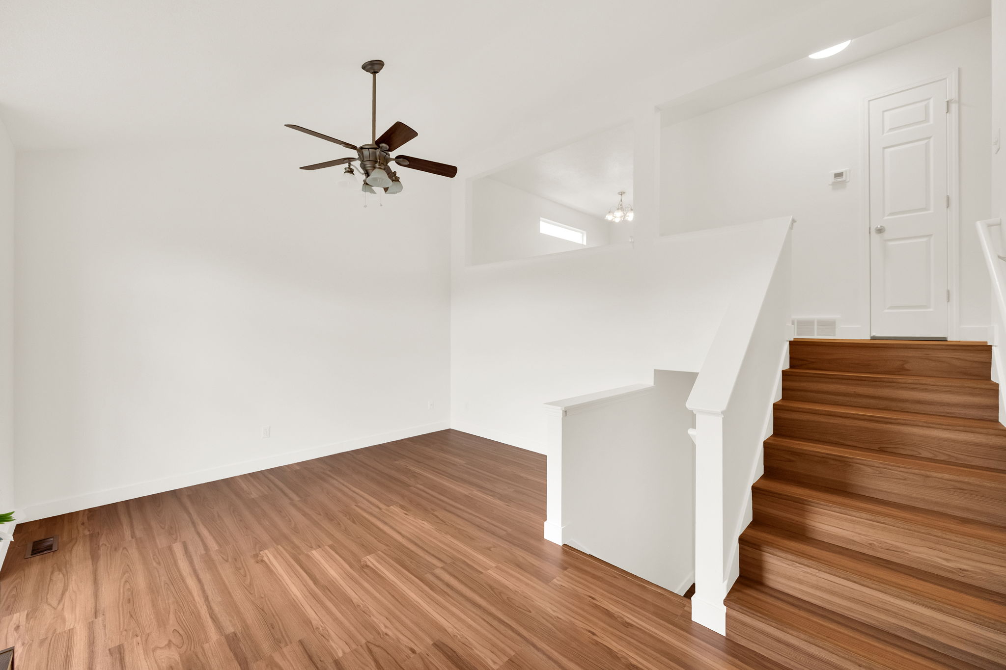 Open-concept living space featuring wood-finish flooring, a contemporary ceiling fan, and a bright white interior