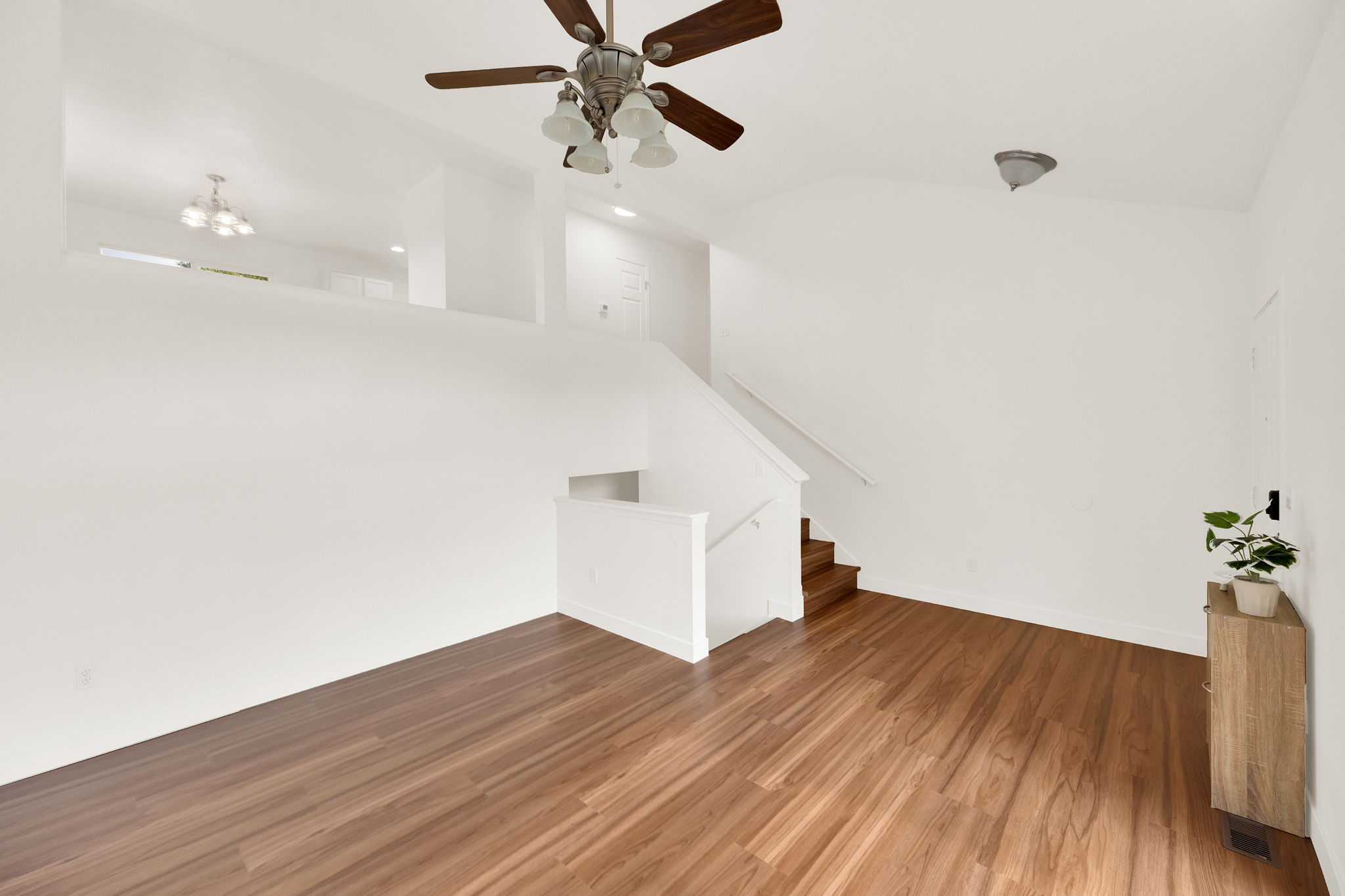 Open-concept living space featuring wood-finish flooring, a contemporary ceiling fan, and a neutral color palette
