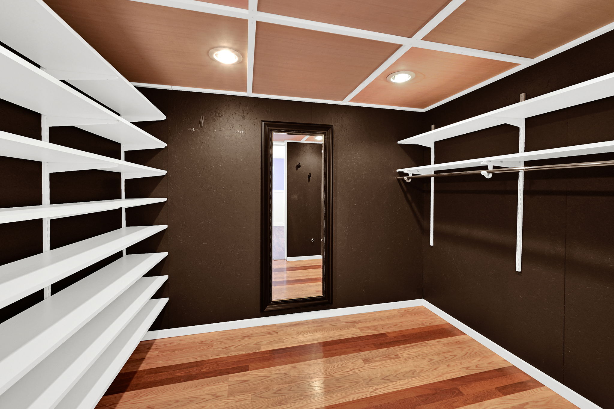 Walk-in closet featuring wood-finish flooring, dark-toned walls, and a coffered ceiling with recessed lighting
