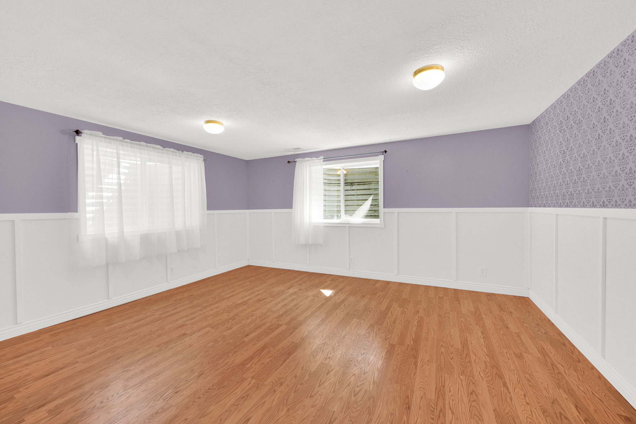 Wood-finish flooring throughout, complemented by white wainscoting and lavender-painted walls