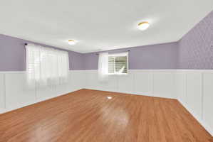 Wood-finish flooring throughout, complemented by white wainscoting and lavender-painted walls