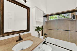Bathroom featuring a framed vanity mirror, single basin sink with bronze-finish faucet, and white cabinetry