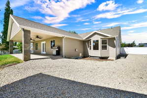 Expansive covered patio with concrete flooring, stone-clad columns, and dual ceiling fans