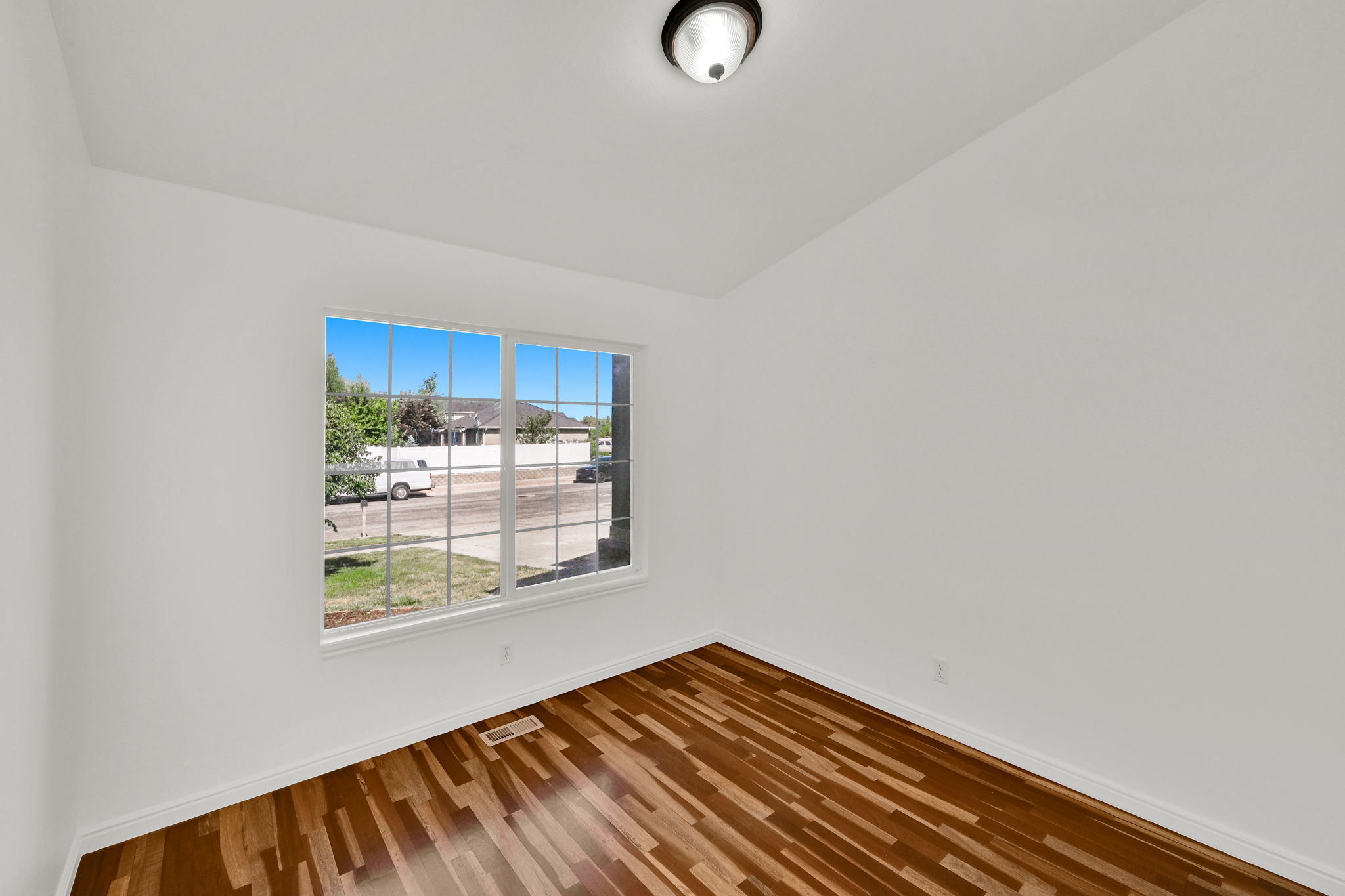 Bright room with wood-finish flooring, white walls, and a multi-pane window