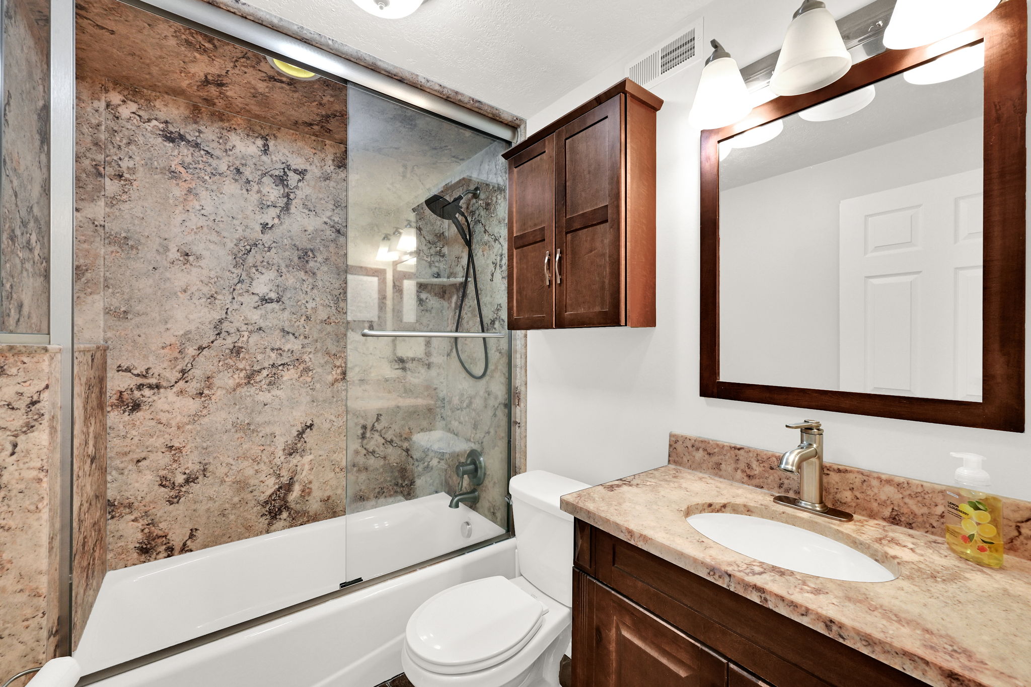 Bathroom featuring a full vanity with an integrated sink, stone-look countertop, and dark wood-finish cabinetry