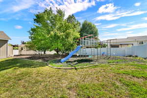 Expansive backyard with a play structure, mature trees, and a wooden storage shed
