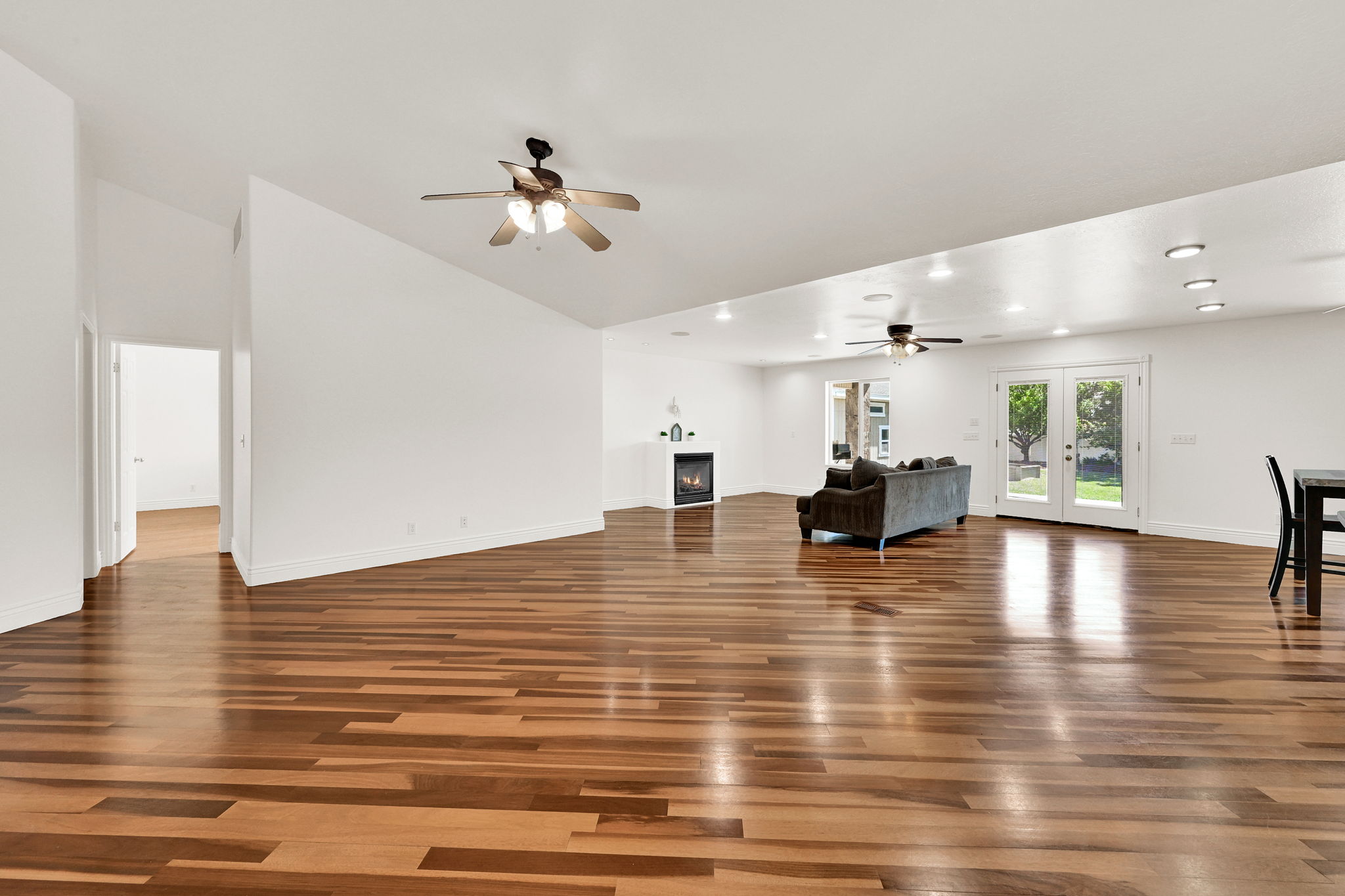 Spacious room with wood-finish flooring, white walls, and a vaulted ceiling