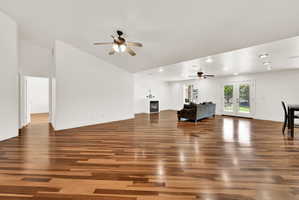 Spacious room with wood-finish flooring, white walls, and a vaulted ceiling