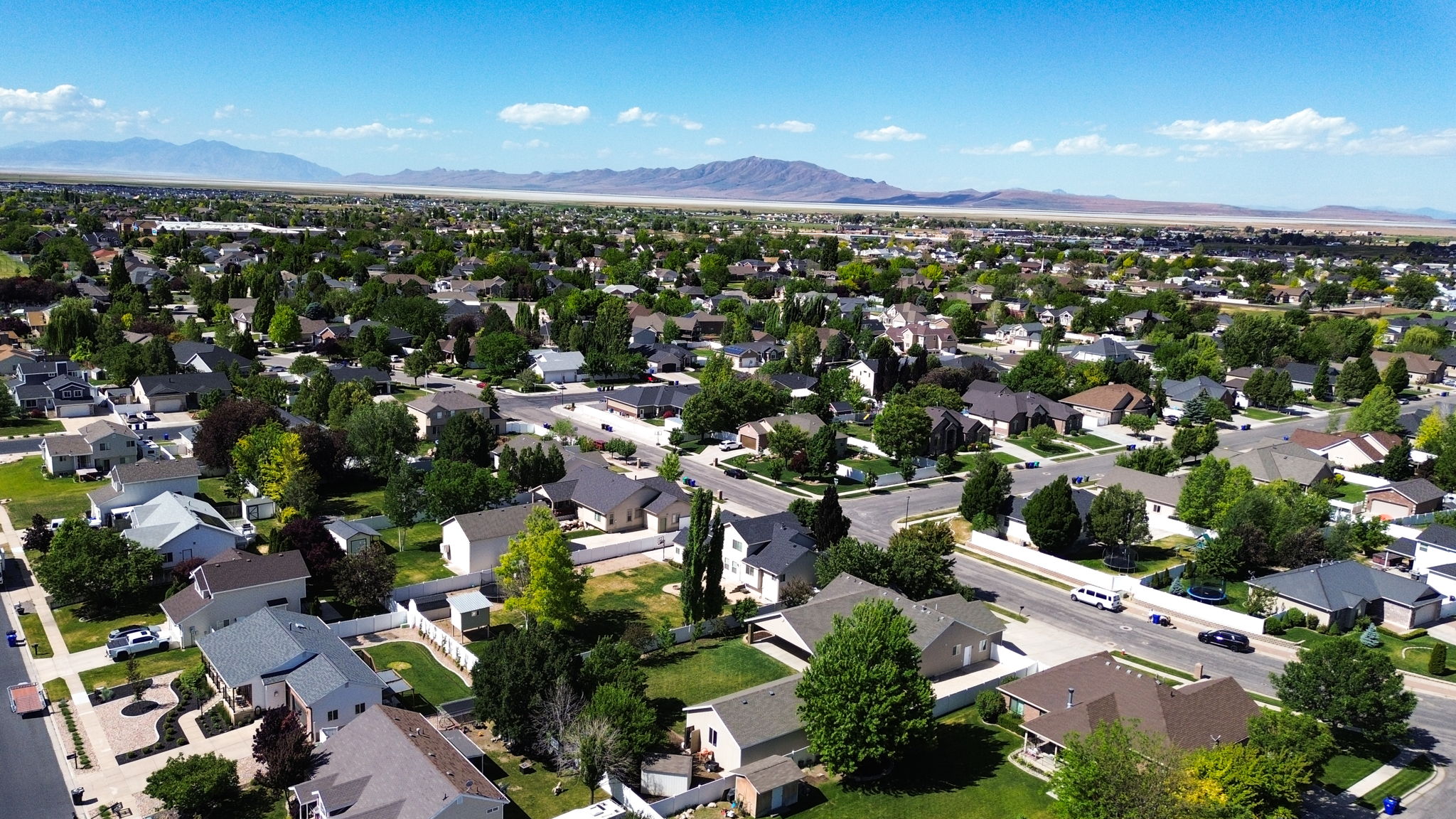 Expansive aerial perspective showcasing a residential neighborhood with a variety of single-family homes, mature trees, and paved streets