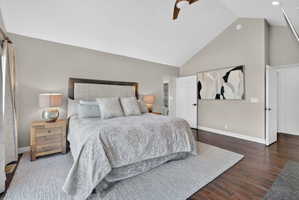 Vaulted ceiling room with wood-finish flooring, light grey wall paint, and white trim