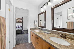 Dual vanity with granite countertops, integrated sinks, wood cabinetry, and oil-rubbed bronze fixtures