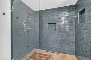 Spacious walk-in shower featuring subway tile walls, a glass enclosure, and a linear drain