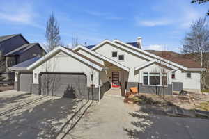 Contemporary stucco exterior with a multi-car garage, prominent entry with a red door, and multiple rooflines