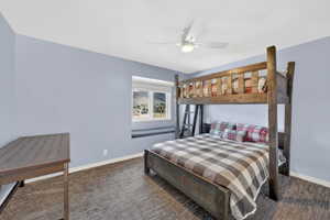 Room featuring wood-finish flooring, a window with a built-in bench, a ceiling fan with integrated lighting, and light blue wall tones