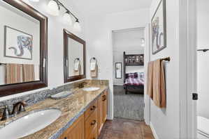 Dual vanity with a stone countertop, bronze-finish fixtures, and framed mirrors