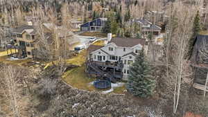 Elevated property featuring multiple levels of outdoor decking, a terraced yard, mature evergreen trees, and a sloped, natural landscape