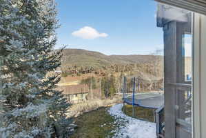 Mountainous backdrop with distant residences and a partially snow-covered lawn