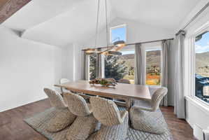Dining area featuring vaulted ceilings, wood-finish flooring, and expansive windows